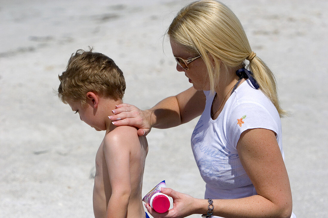 Mother applying sunscreen to son