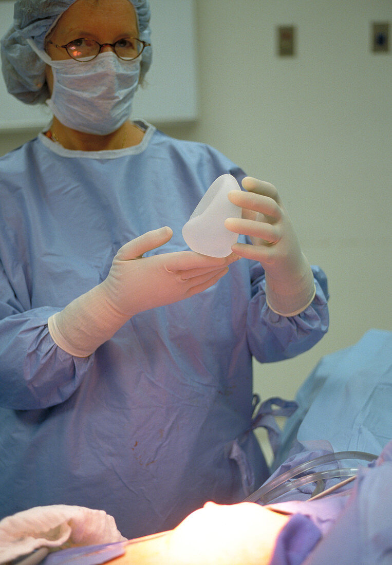 Surgeon holds a breast implant