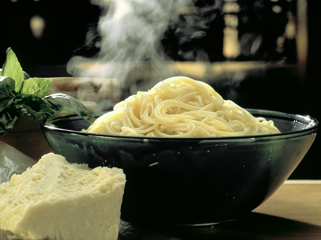Dampfende Spaghetti in Schüssel & ein Stück Parmesan