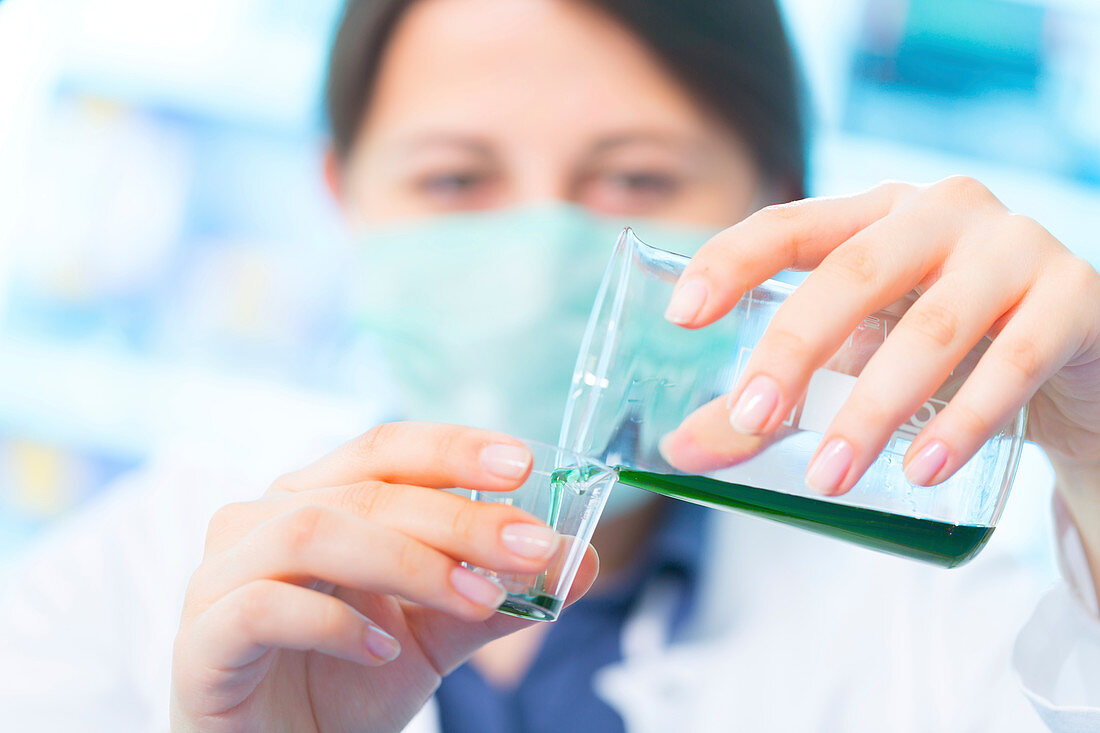 Scientist pouring green liquid into a cup