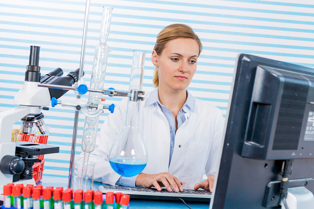 Female chemist using computer in lab