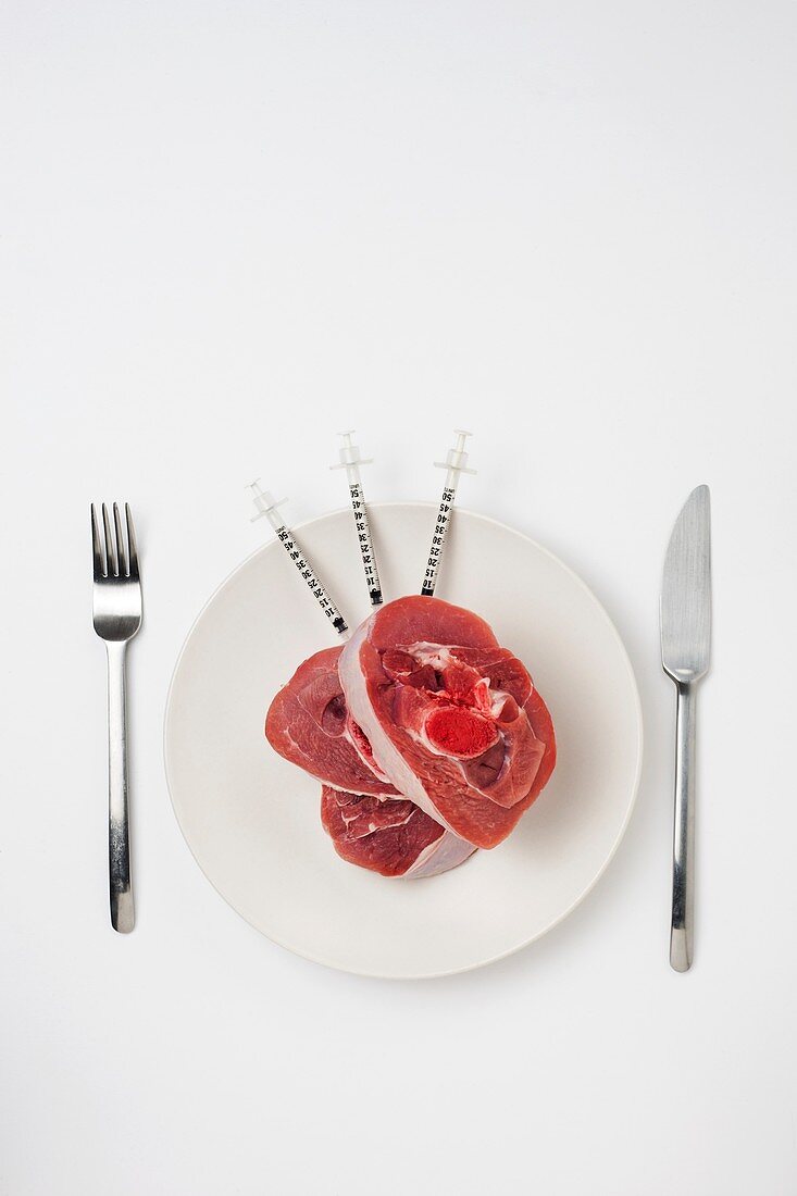 Red meat with syringes on a white plate