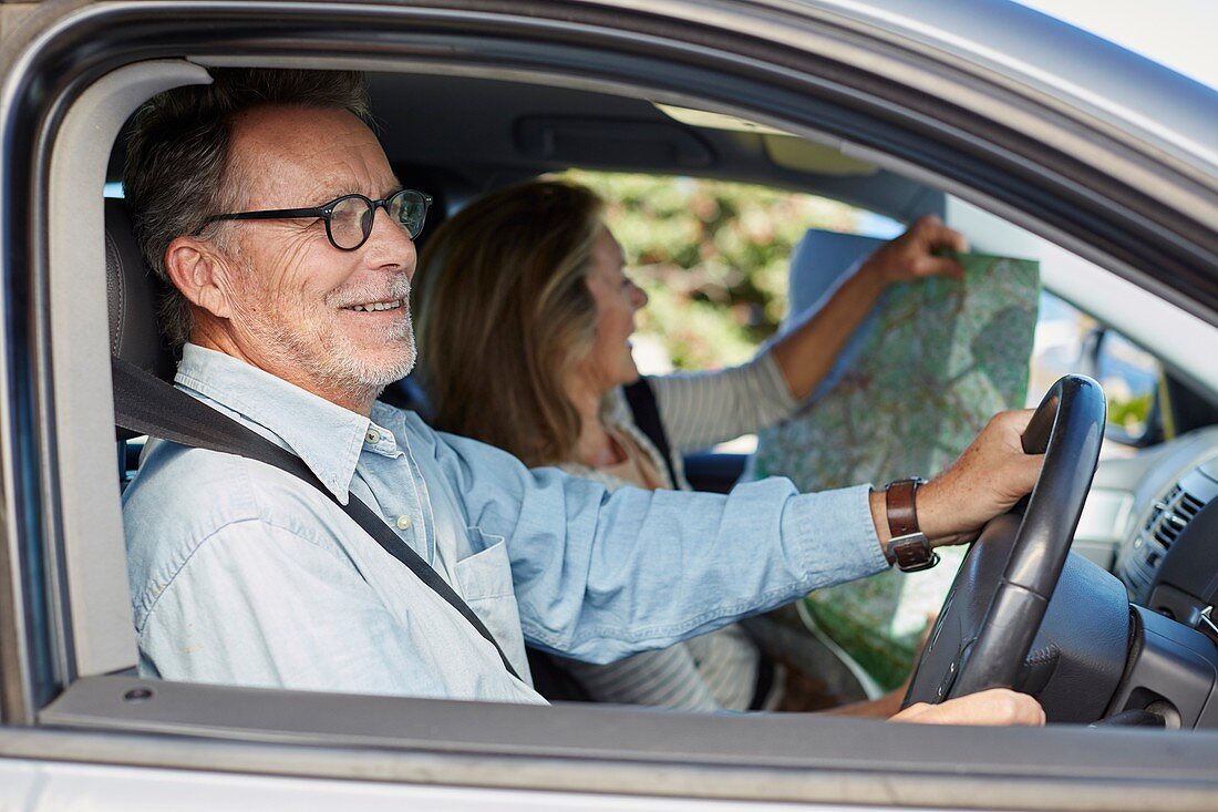 Senior man in car,woman holding map