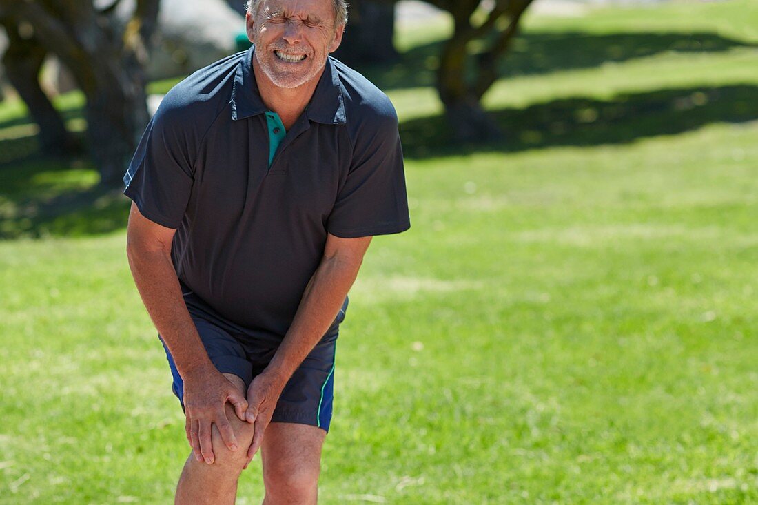 Senior man holding his knee in pain