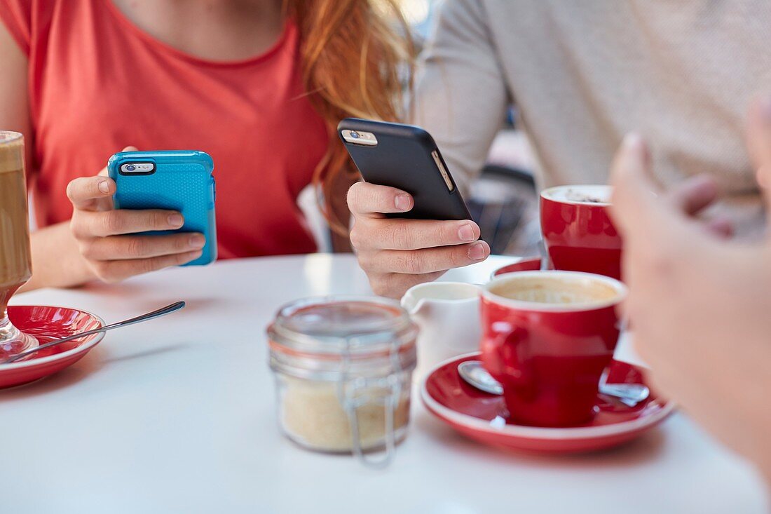 Young people in cafe using smartphones