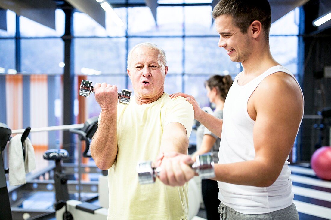 Man holding dumbbell with trainer support