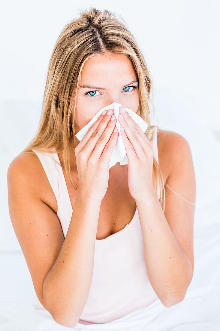 Woman with a cold using tissue