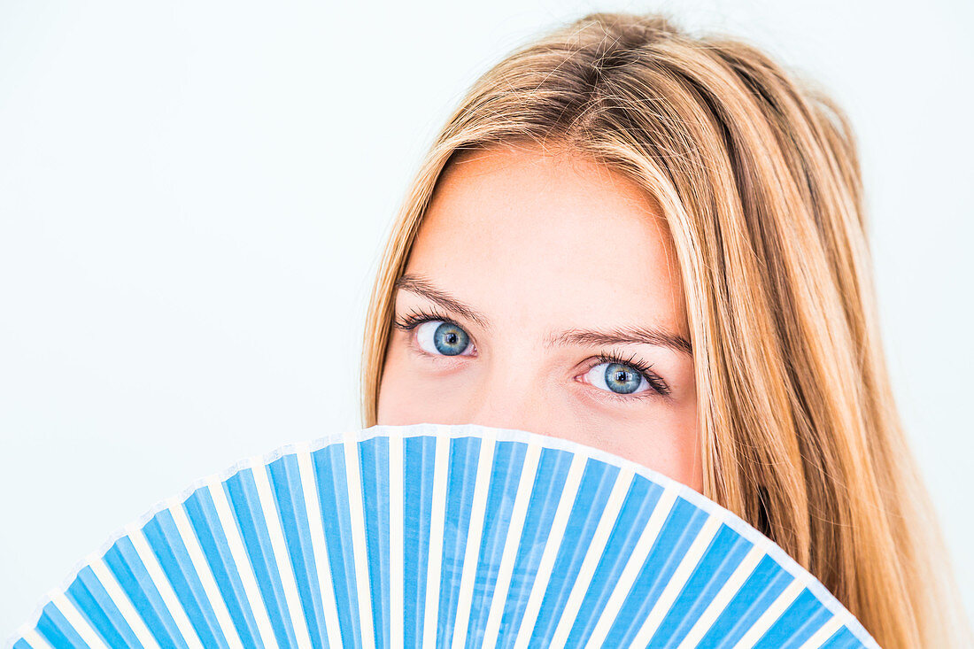 Woman cooling her face with a fan