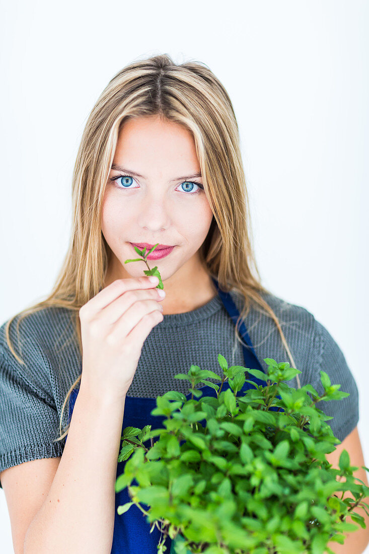 Woman smelling mint leaves (Mentha sp)