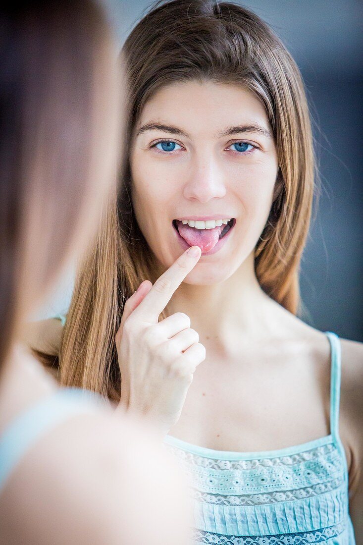 Woman examining her tongue in a mirror