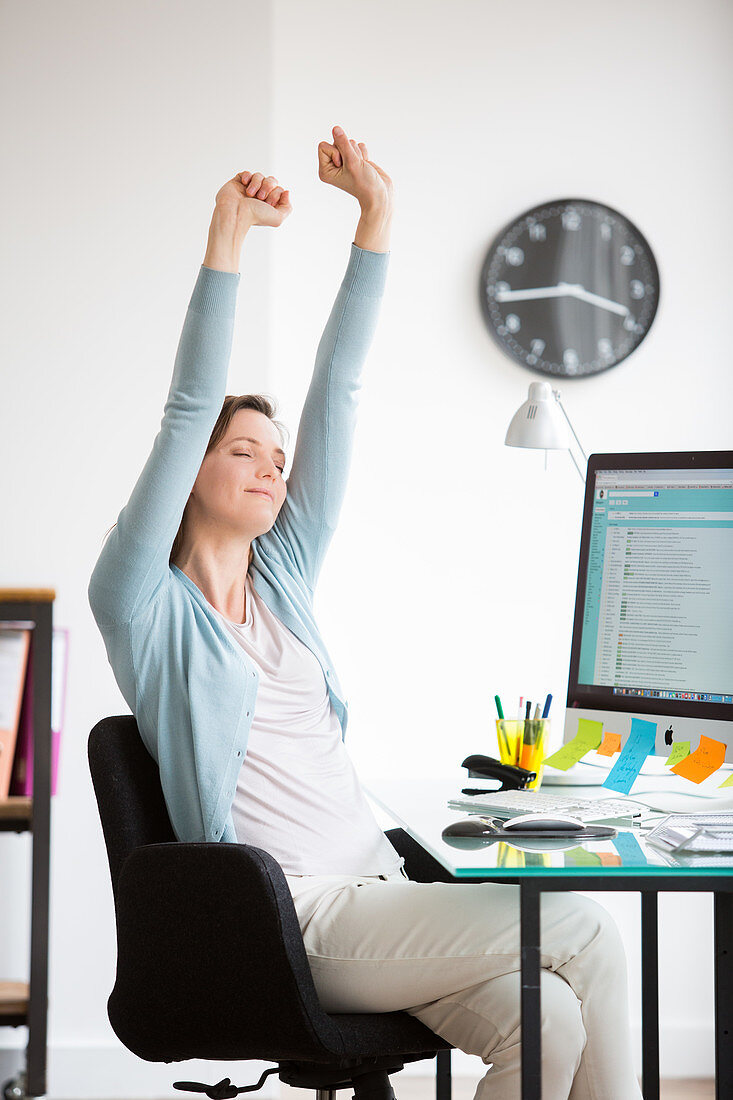 Office woman stretching arms at work