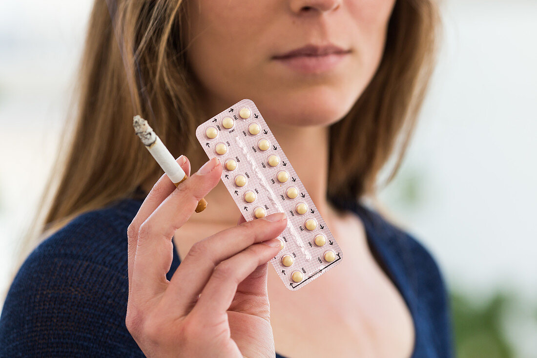 Woman holding contraceptive pills and cigarette
