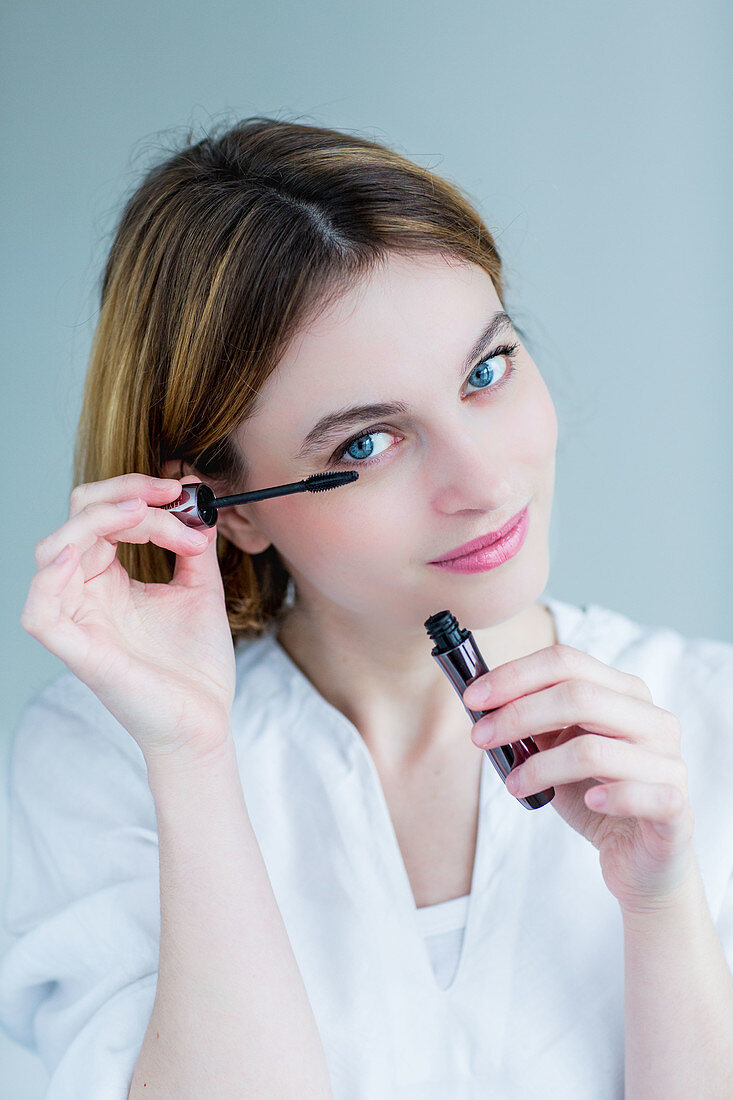 Woman applying mascara on her eyelashes