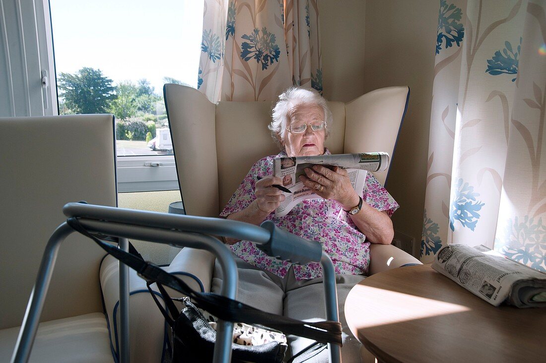 Care home resident reading newspaper