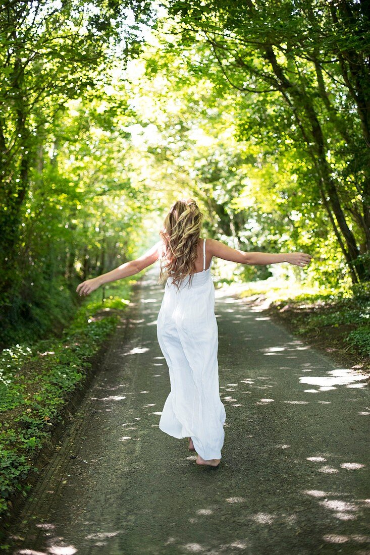 Woman in long white dress on country lane