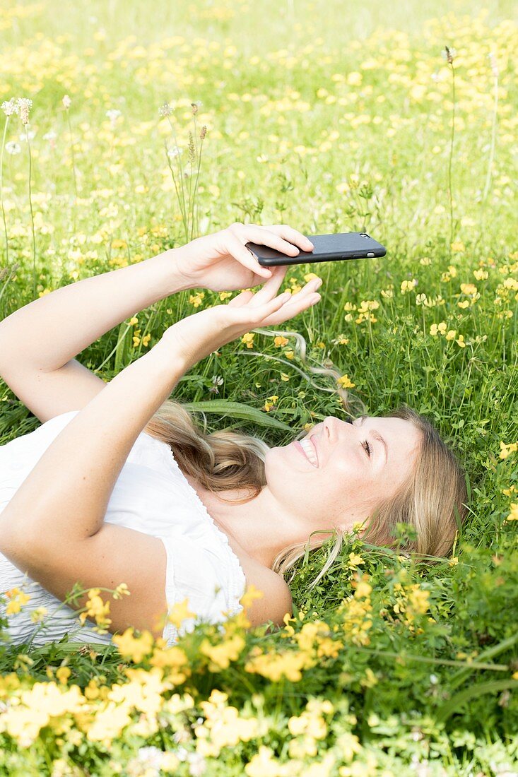 Woman lying on grass with cell phone