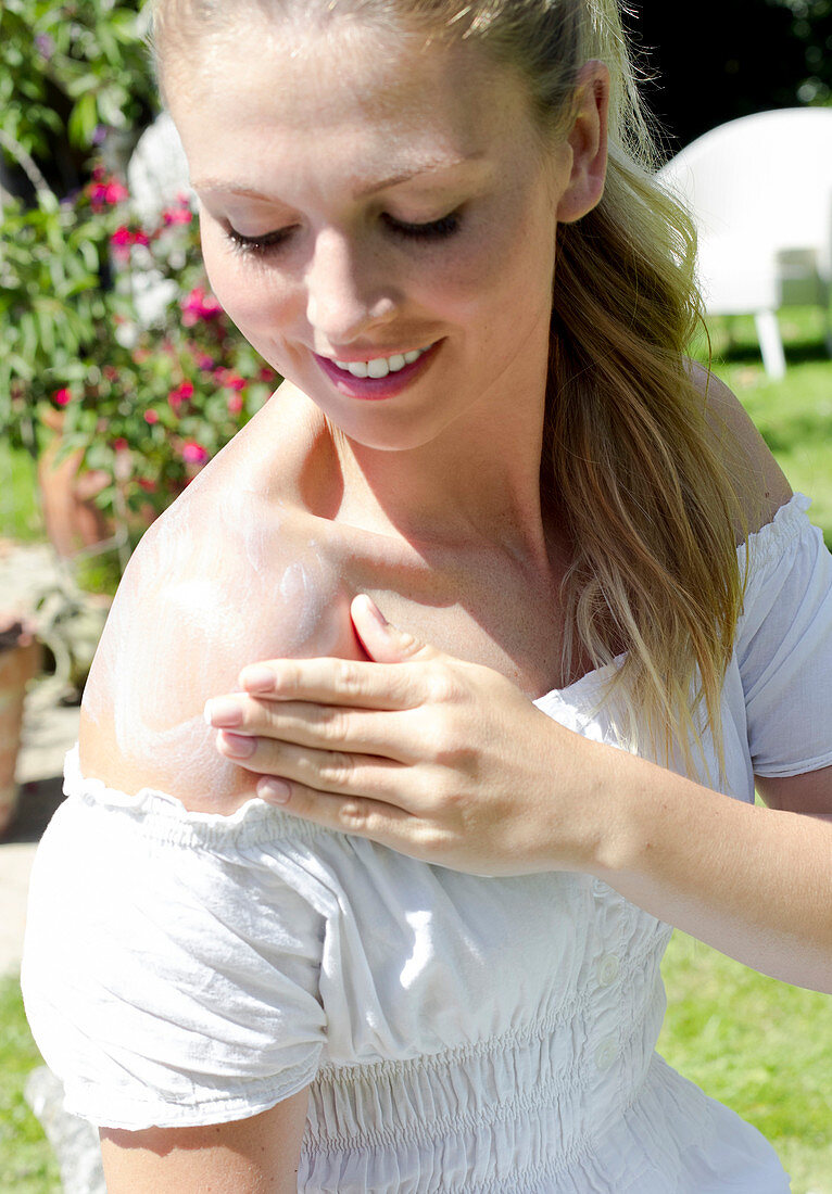 Woman rubbing sun cream on shoulder