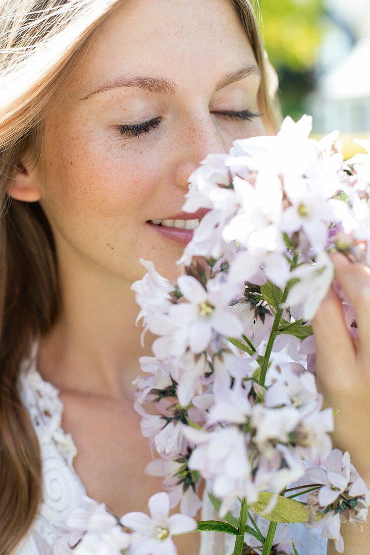 Woman smelling white flowers