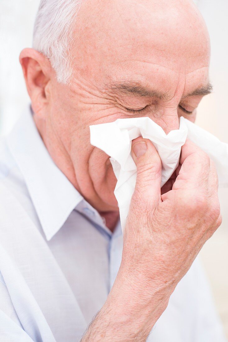 Man blowing nose on tissue