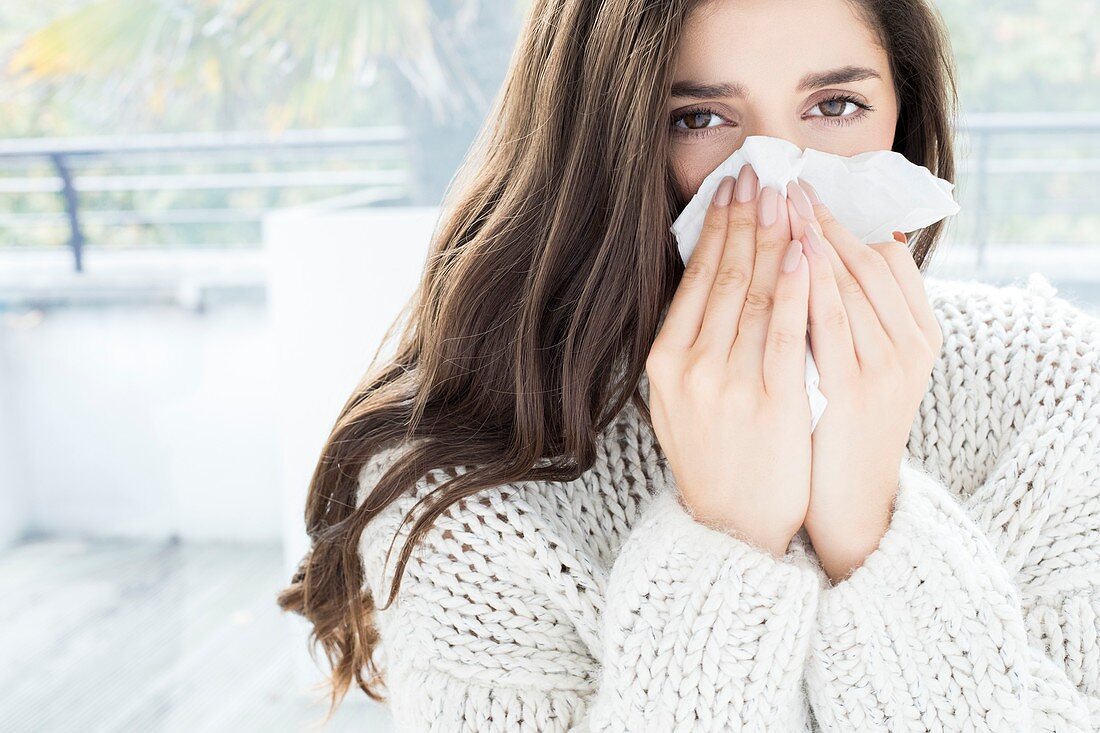 Woman blowing nose on tissue