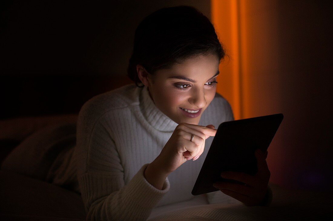 Woman using digital tablet in dark room