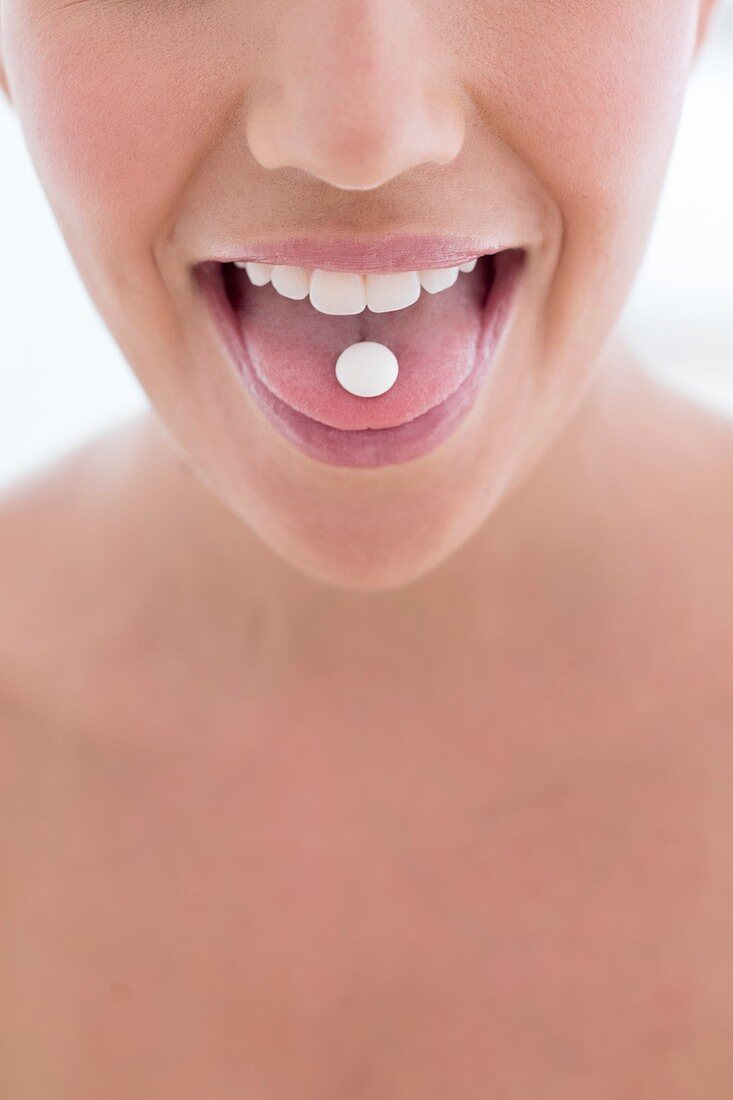 Woman with pill on tongue