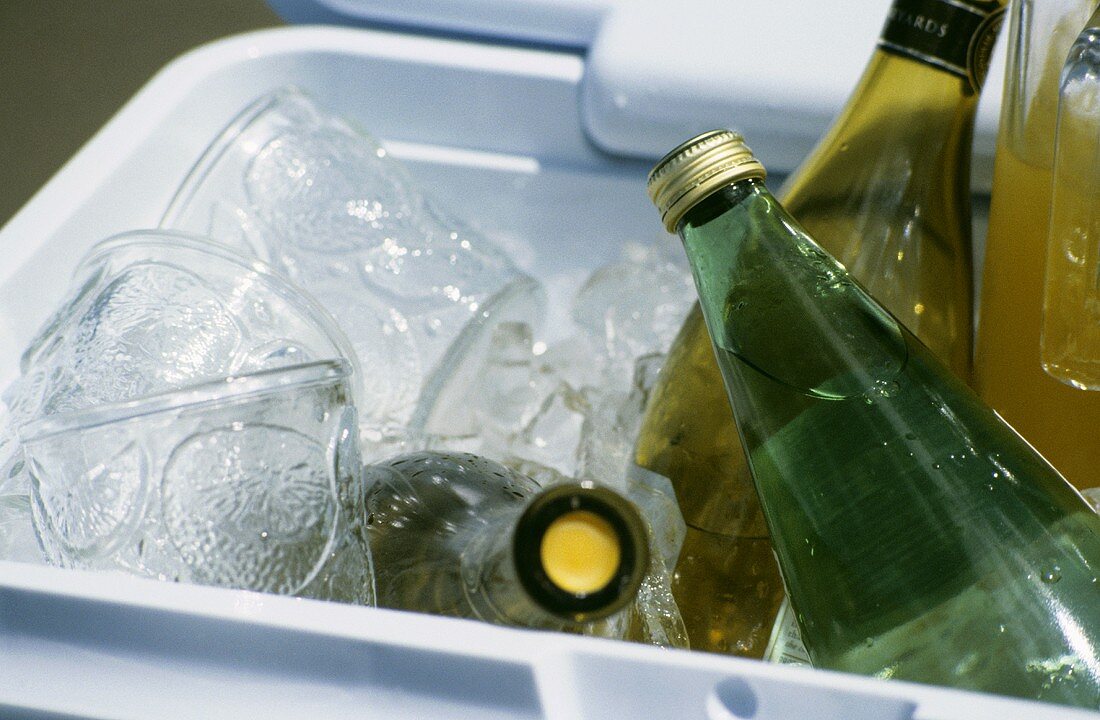 Assorted Bottled beverages and Glasses in a Cooler