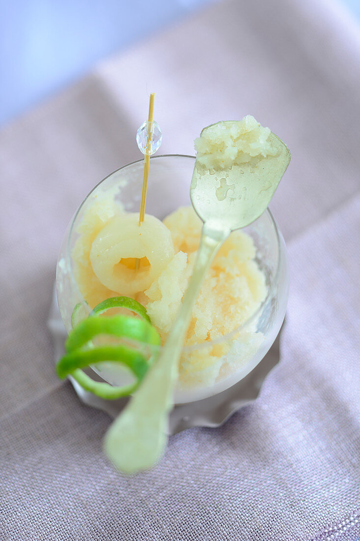 Lychee ice cream in a glass with a spoon and lime peel