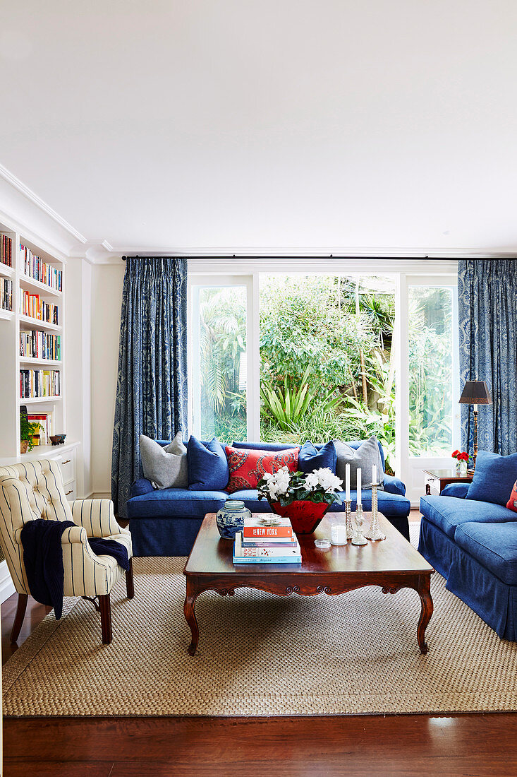 Blaue Polstergarnitur, antiker Couchtisch und Sessel im Wohnzimmer