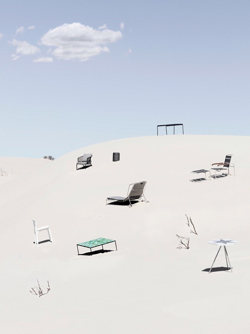 Gartenmöbel auf einsamer Flur im Sand unter blauem Himmel