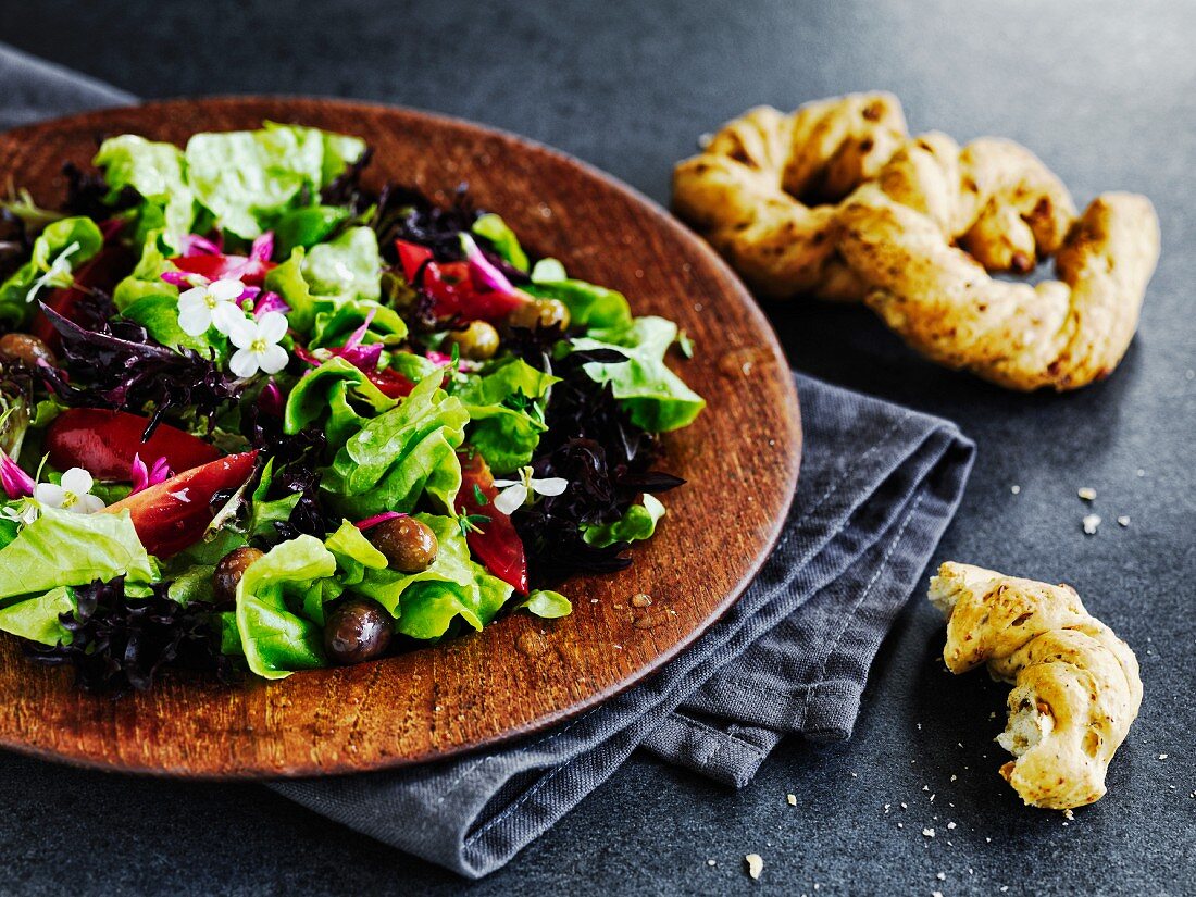 Mediterraner Blattsalat mit Tomaten und Oliven serviert mit Brot