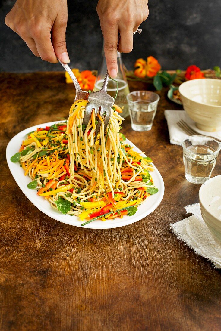 A woman is serving Asian Sesame Pasta Salad served with white wine