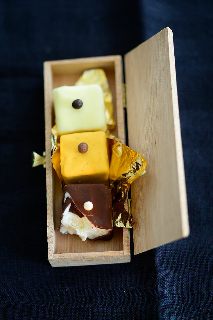 Petit fours with gold foil in a wooden box
