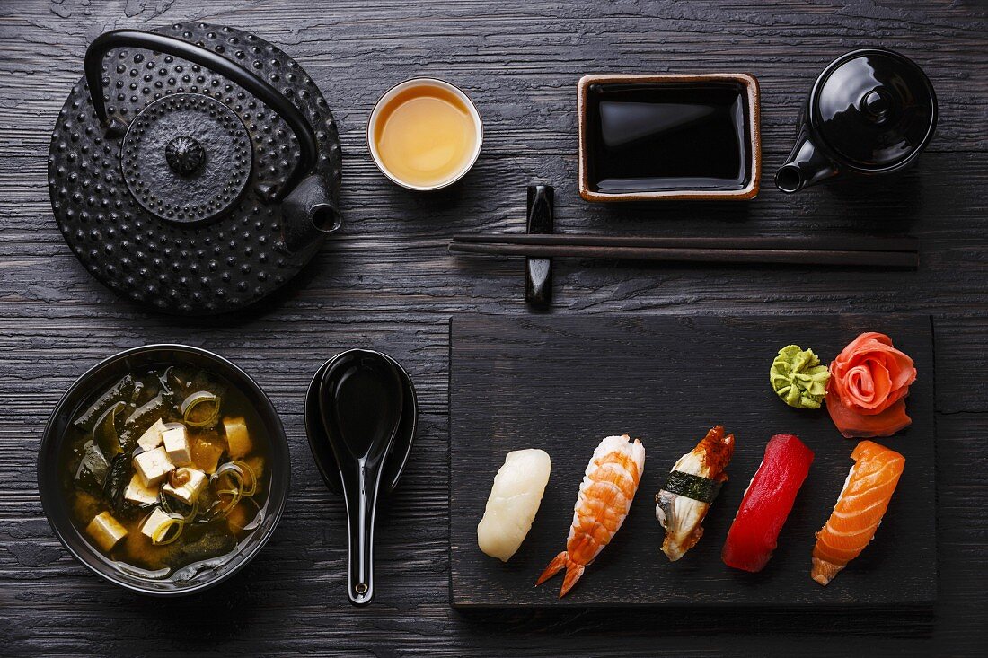 Nigiri Sushi set on wooden serving board and Miso soup on black wooden background