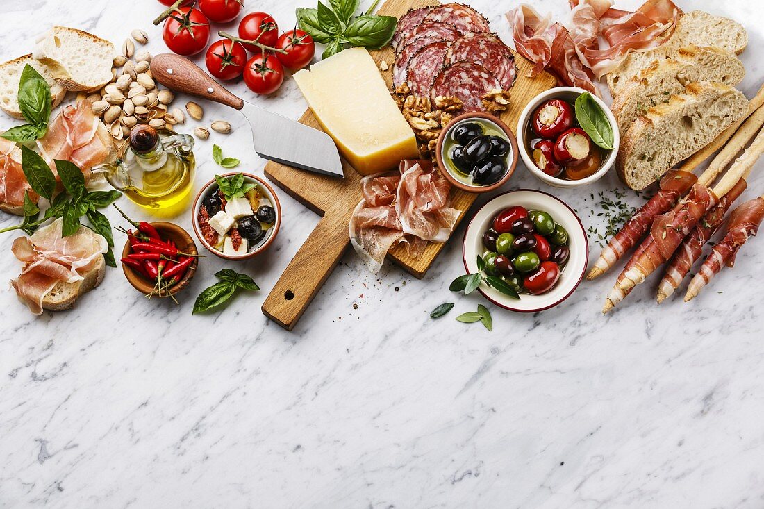 Italian snacks food with Ham, Sliced bread Ciabatta, Olives, Parmesan cheese, Grissini bread sticks, Feta cheese with dried tomatoes and Sausage