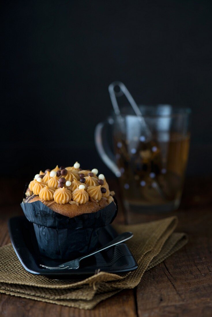 A salted caramel cupcake with a cup of herbal tea