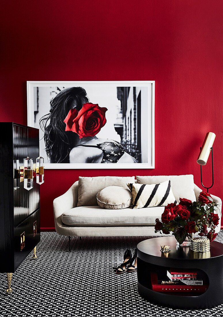 Schwarzer Coffeetable, schwarzer Schrank und helles Sofa im Wohnzimmer mit roter Wand