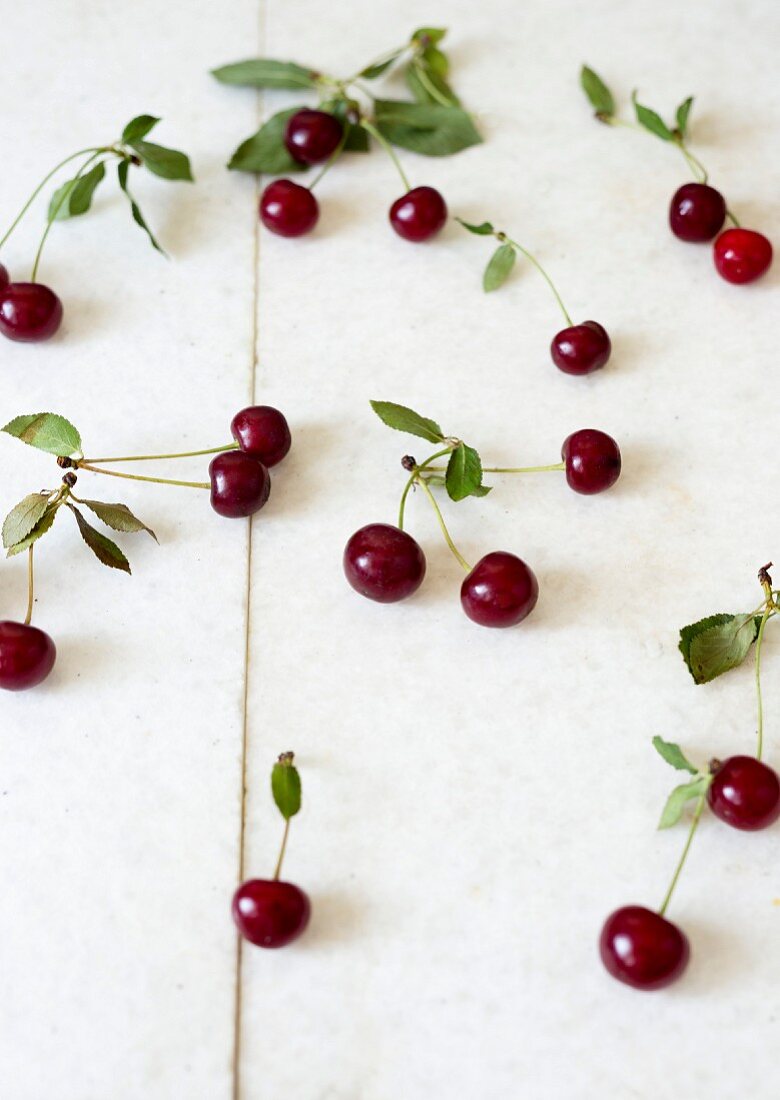 Cherries with leaves on a white surface