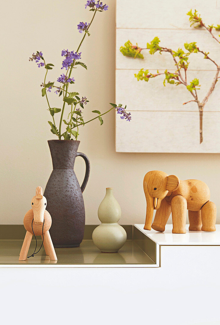 Tierfiguren aus Holz und Keramikvasen auf Sideboard