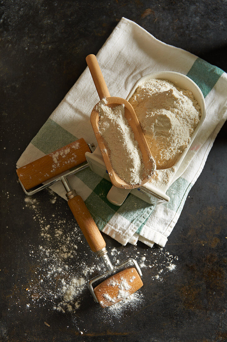 Flour in an old ceramic drawer with a wooden scoop and a rolling pin