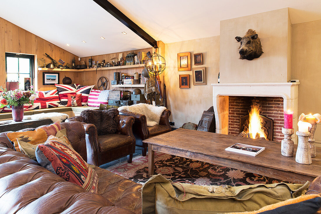 Vintage Ledercouch, Sessel und Couchtisch vor Kamin in umgebauter Scheune