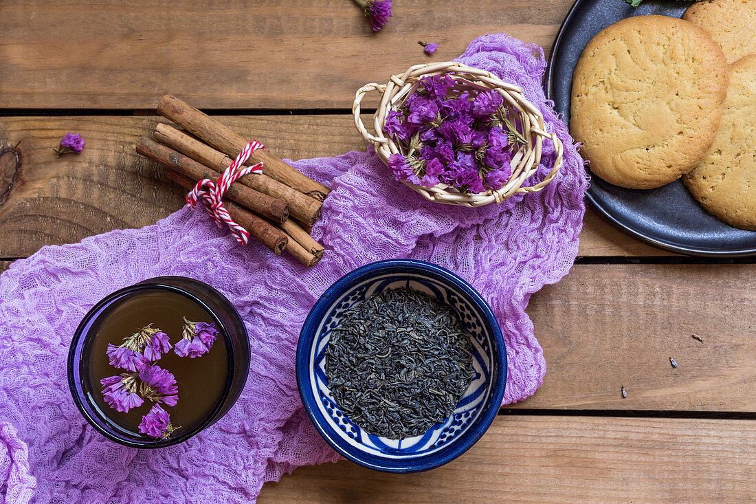 Green tea with cinnamon sticks, edible flowers and biscuits