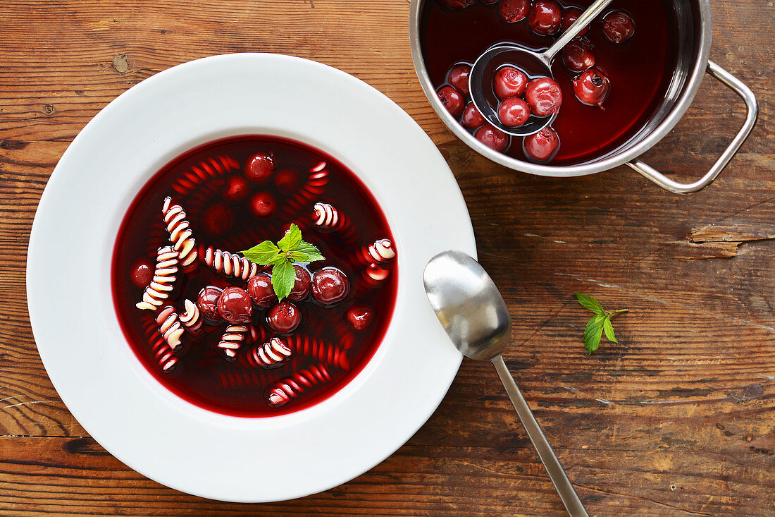 Cherry soup with noodles in a bowl and a saucepan