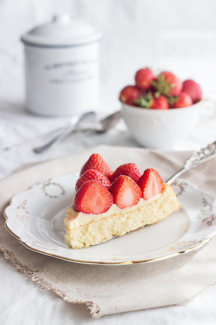 A slice of strawberry cake topped with set custard