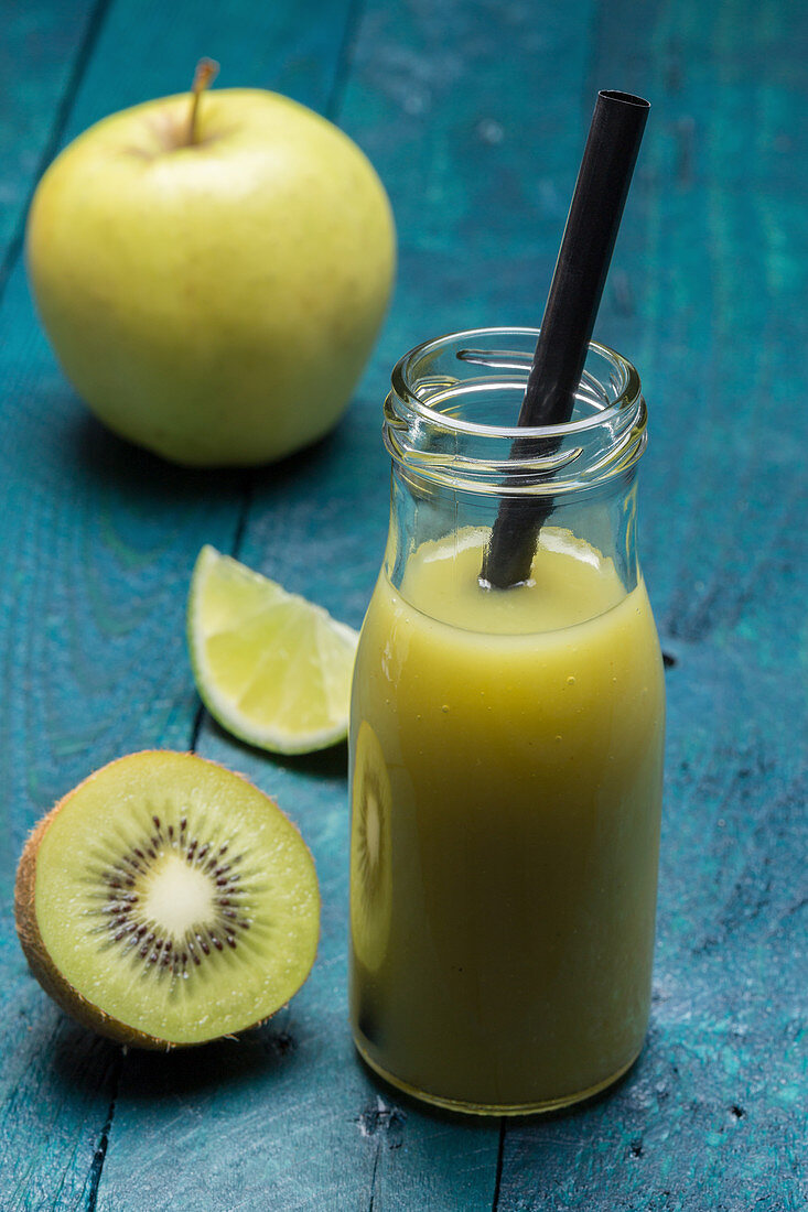 A kiwi and apple smoothie with lime in a bottle with a straw