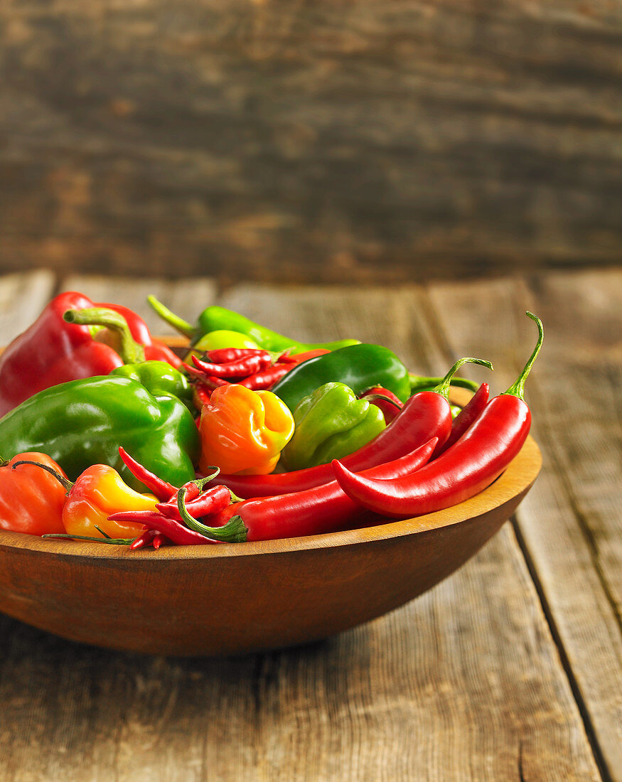 Sweet and chili peppers in a wooden bowl