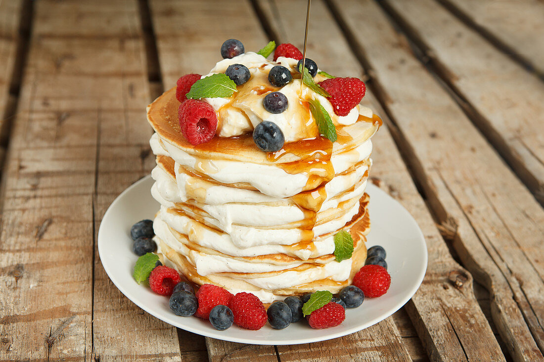 Pancake cake with orange cream, maple syrup and berries
