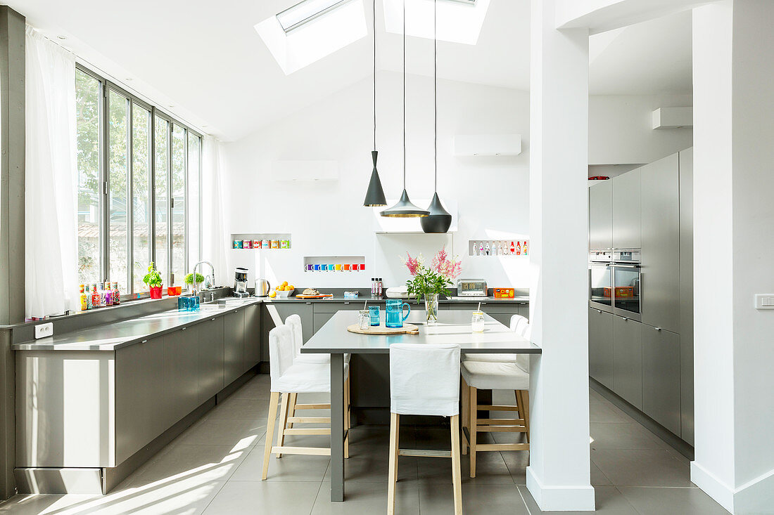 Elegant grey and white kitchen with glass wall and dining area