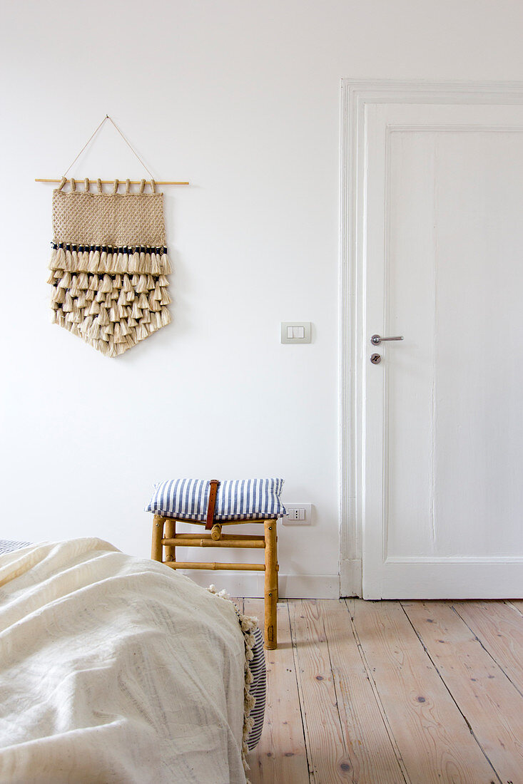 Schlafzimmer mit Holzdielenboden, Handarbeit an weißer Wand