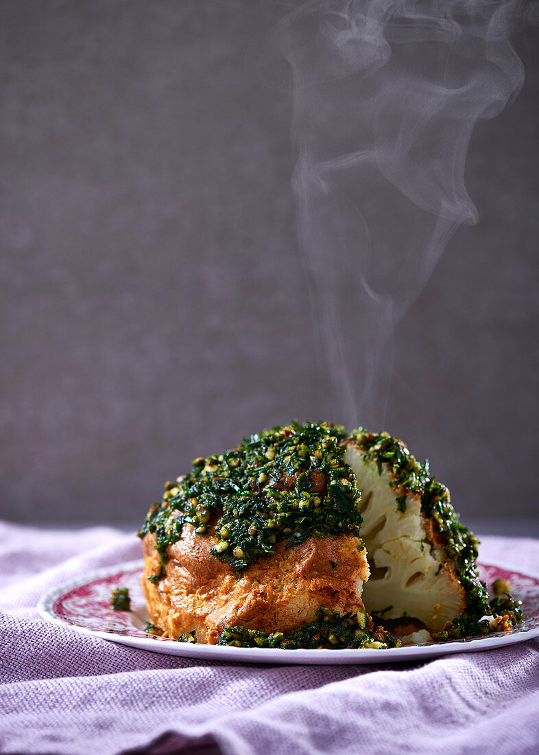 A whole cauliflower in a Tahini spice crust with almond and herb pesto